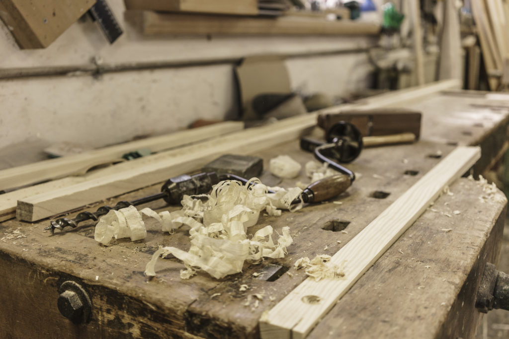 Mechanic drill, plane and wood shavings lying on workbench at carpentry workshop